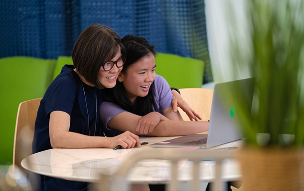 adult woman and girl looking at a laptop